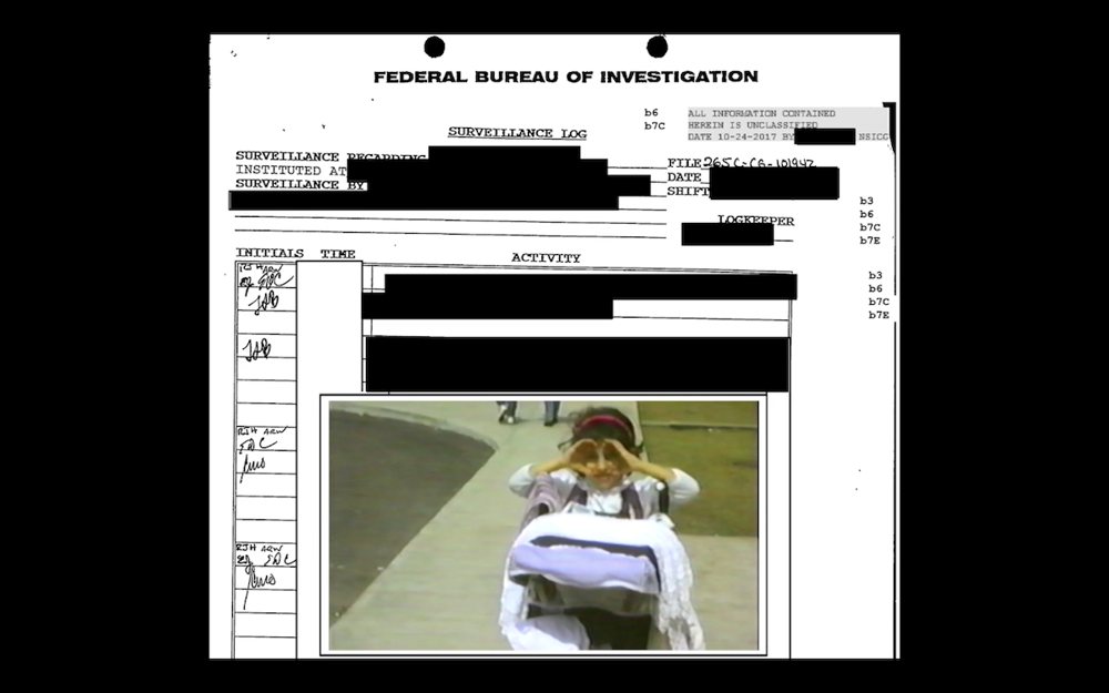 A photo of a redacted FBI document. At the bottom is a color photograph of a young girl who has her hands raised, encircling her eyes like goggles.