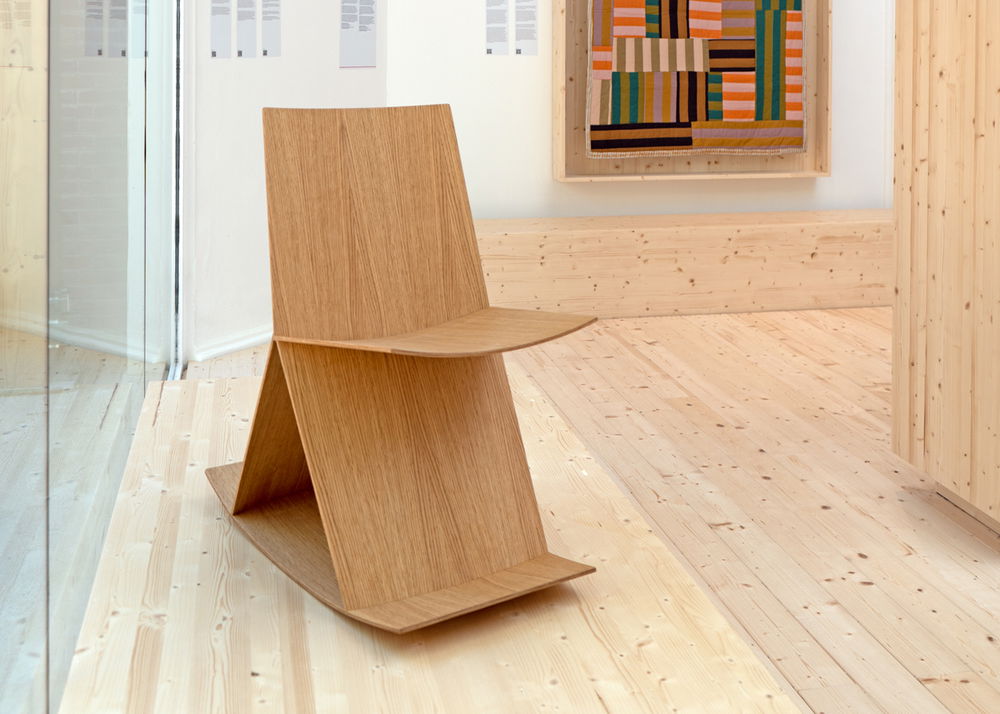 A molded plywood rocking chair in a gallery.