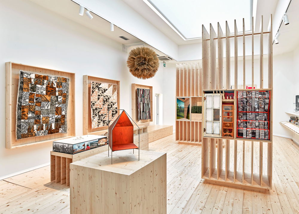 Gallery installation featuring colorful quilts and various sculptures.