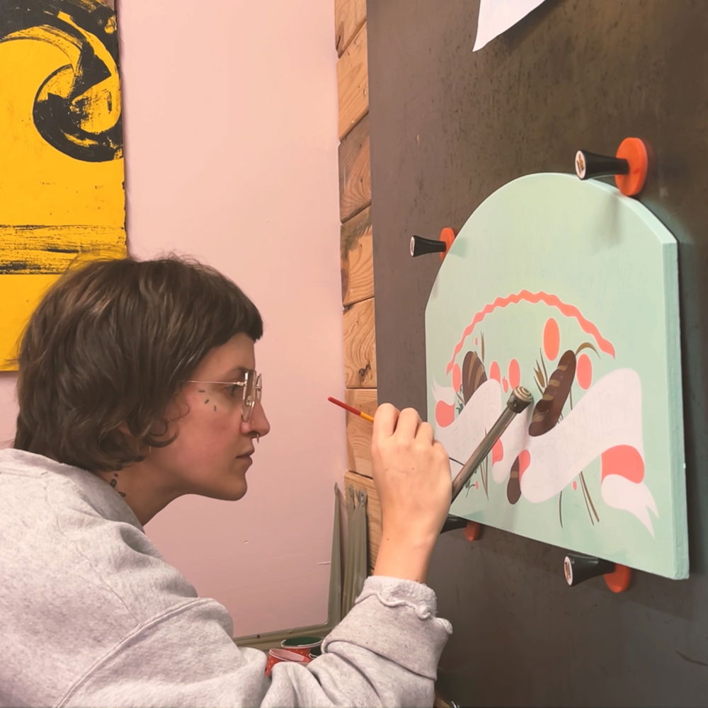 A person using a mahl stick to support their wrist as they begin painting.
