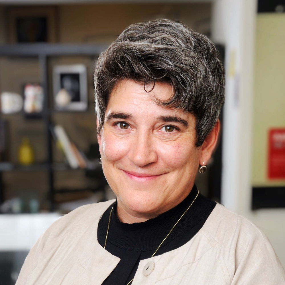 A white woman with short hair smiles warmly.