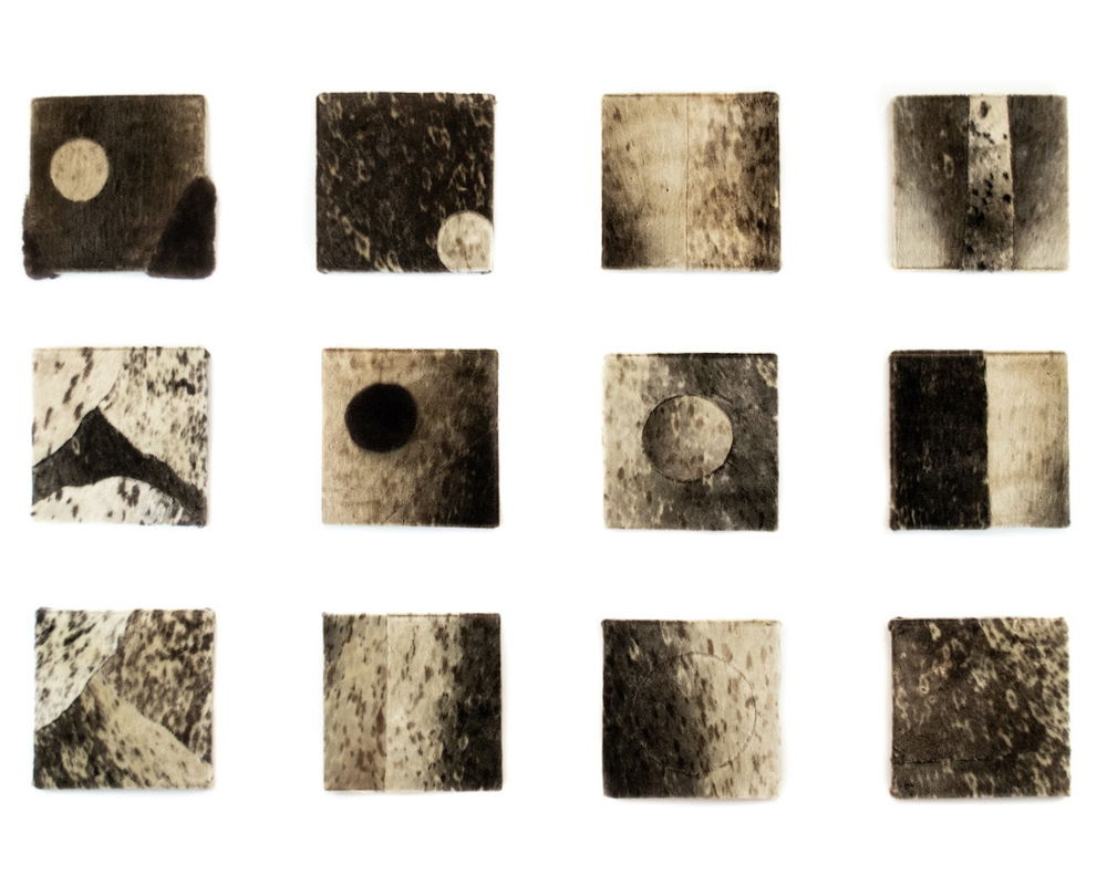 Twelve small squares made of sewn furs and skins of different colors and textures. Circles and orbs repeat in many of the drawings creating patterns like moon craters or cells under a microscope.