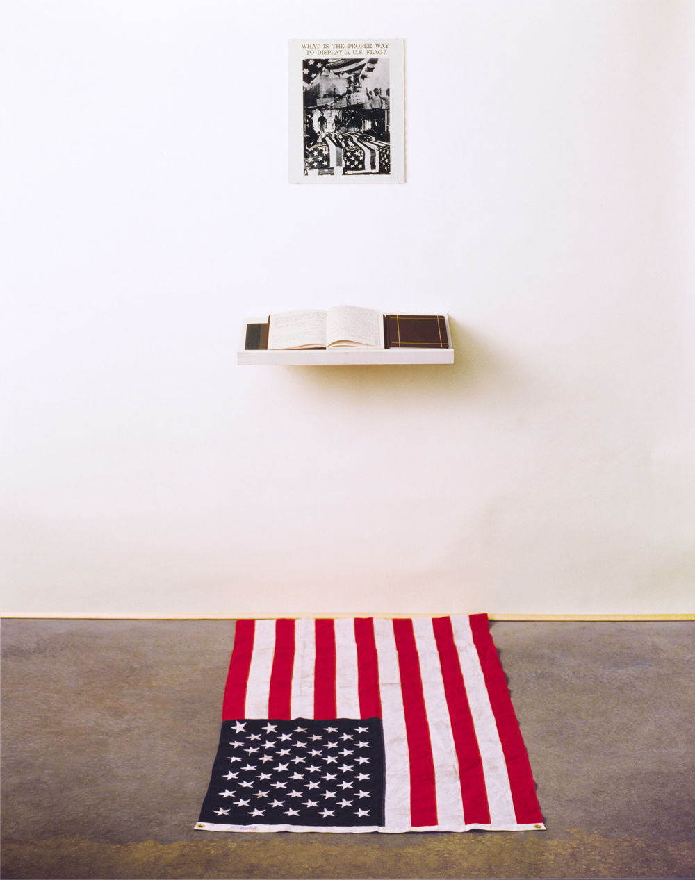 What is the Proper Way to Display a US Flag? installation: silver gelatin print, books, pens, shelf, active audience, US flag, 80 x 28 x 12 inches, 1988.