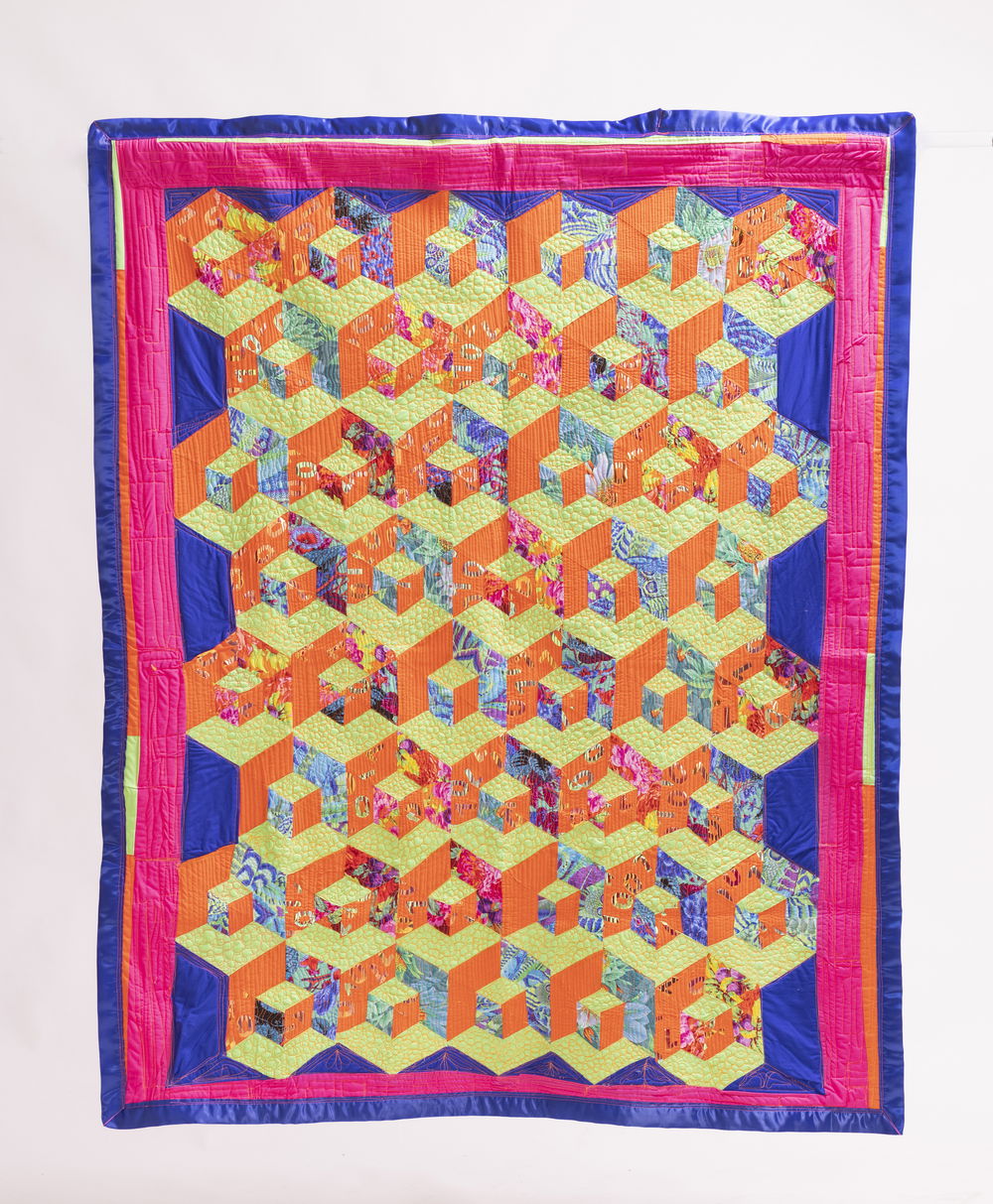 A rectangular fabric quilt made up of a stacked hexagonal pattern, forming a three-dimensional cubic illusion with eight rows of richly textured light blue, orange, and light green patterned diamonds. Around the edges runs a hot pink border and a satin blue border.