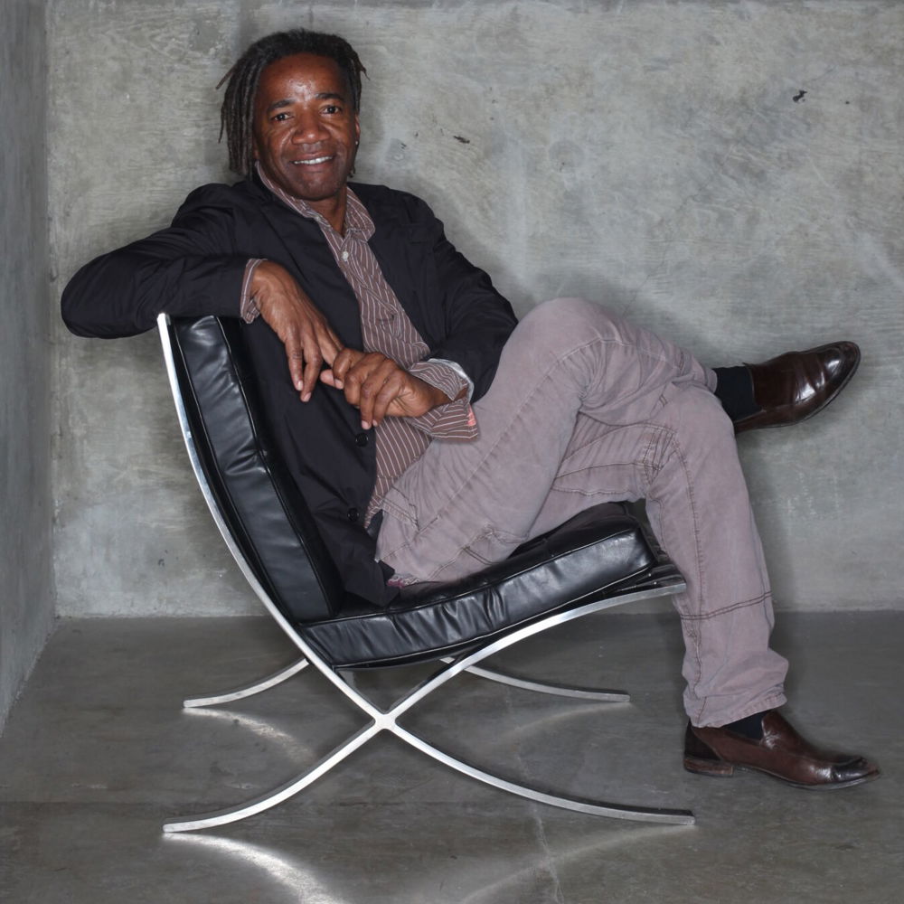 Walter smiles as he sits in a chair surrounded by concrete walls.