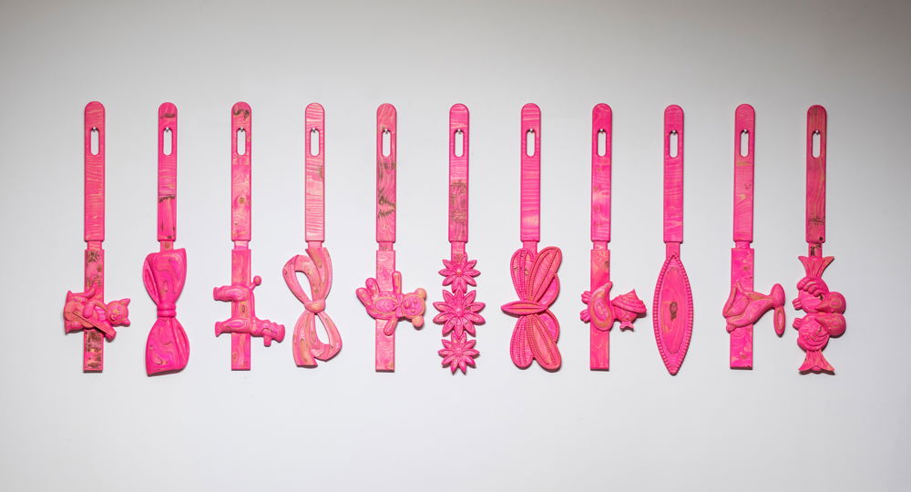 A neat row of 11 giant pink hair barrettes hung from their long clasps and attached to buttons shaped like bows, flowers, and animals.