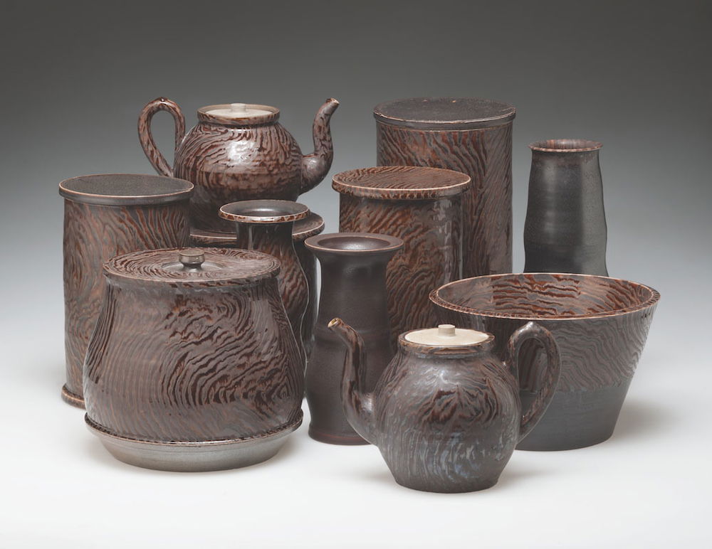 <em>Faux Wood Group</em>, 2014. Porcelain, stoneware, with polychrome glaze trialed pattern, dimensions 16 x 28 x 18 inches. Service Storage Display with teapots, vases, box, and open bowl.