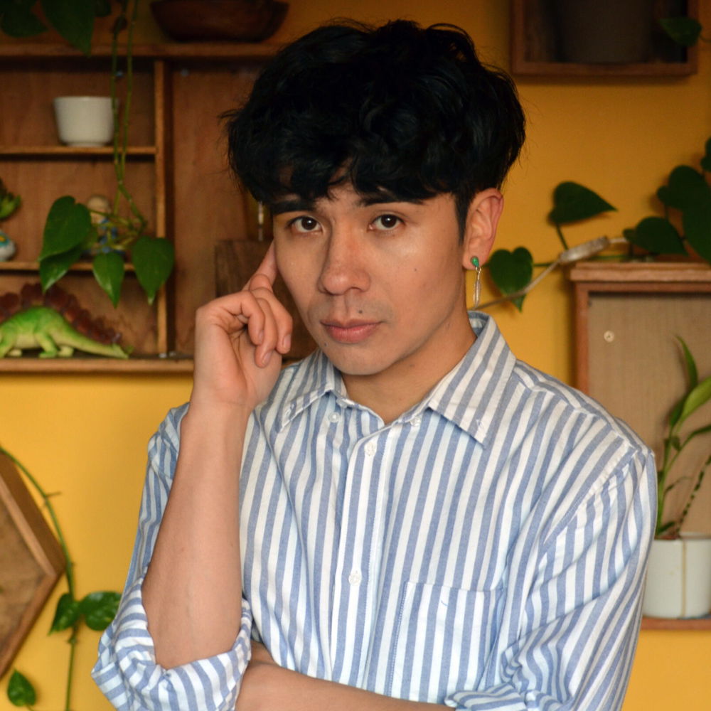 Ocean, a Vietnamese-American man with black undercut-styled hair, is wearing a striped shirt and single dangling earring as he looks at the camera.