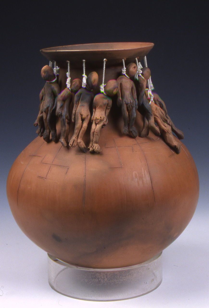 A ceramic vessel in a vase shape. Around the neck of the vase, small figures hang on nooses.