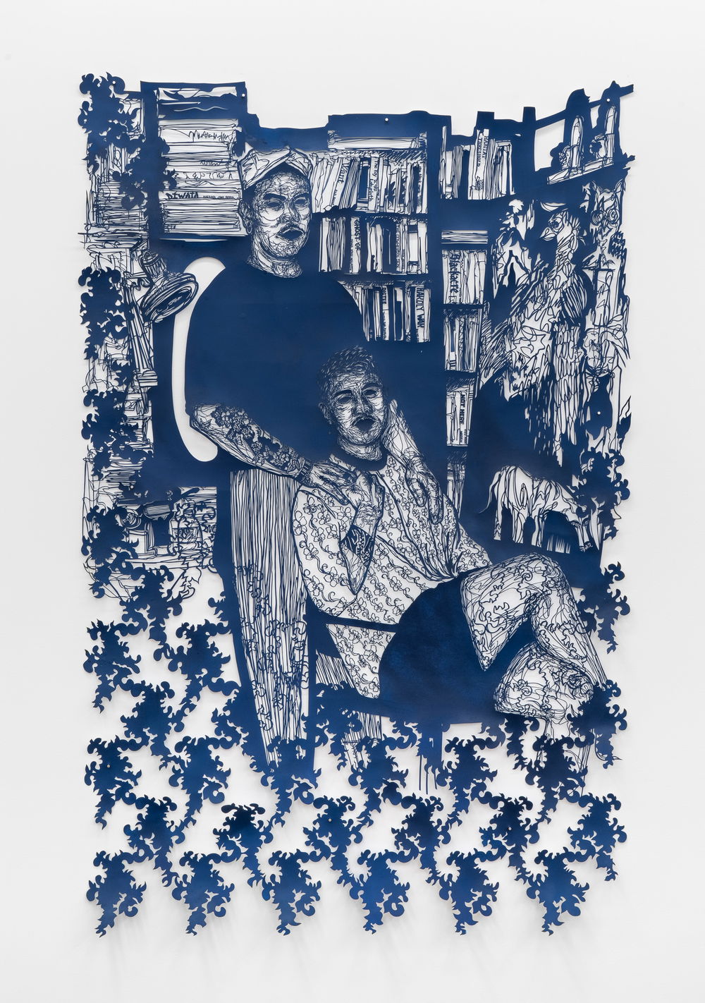 A seated person lightly reclines their head into the stomach of a person standing behind them. The seated person’s legs are crossed and their right hand is raised to grasp the standing person’s hand that is resting on their shoulder. Behind them are shelves of books and a painting of animals that dissolve into an abstract pattern.