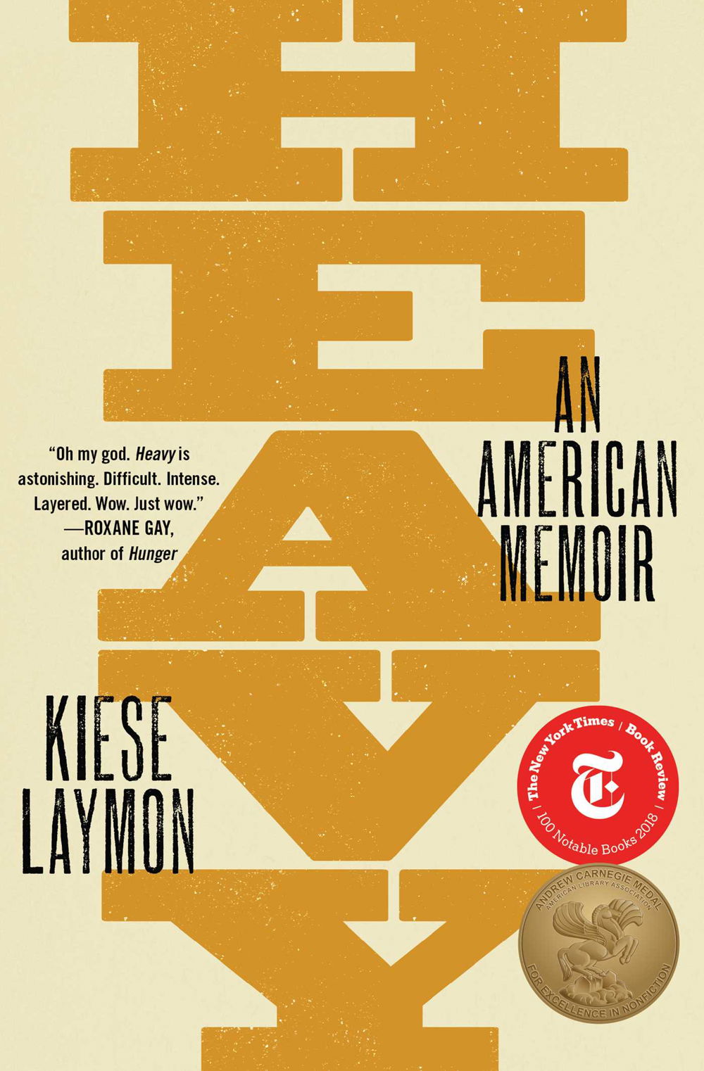 A book cover with the word "Heavy" written in a wide, serif font vertically down the center in a mustard yellow. Black text says "Kiese LAymon" and "An American memoir." Medallions on the cover identify the book as.a New York Times Book Review 100 Notable Books 2018 and Andrew Carnegie Medal for Excellence in Nonfiction.